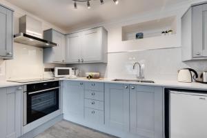a white kitchen with white cabinets and a sink at 1 Bed in West Looe oc-1west in Looe