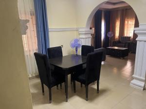 a dining room table with black chairs and a blue fan at Ined Apartment Services in Ibadan