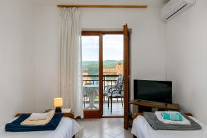 a bedroom with two beds and a tv and a balcony at Apartments Pino Rabac in Rabac