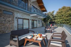 a patio with two chairs and two tables and a couch at Dharohar Retreat, Mukteshwar in Mukteshwar