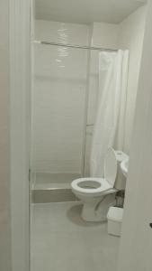 a white bathroom with a toilet and a shower at Astoria Inn Hotel in Toshkent-Passajir Bekati