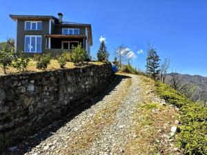 a house on a hill next to a stone wall at ByTemur Dağ Evi in Çamlıhemşin