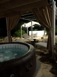 a hot tub under a tent with a table and a chair at Trullo Gio in Cisternino