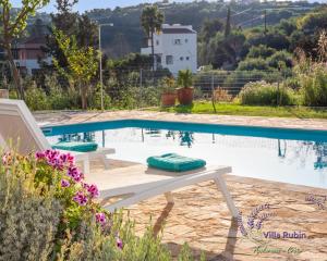a pool with a white bench next to a white house at Villa Rubin in Almyrida