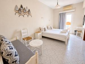 a white bedroom with a bed and a chair at Agia Roumeli Hotel adults only Ξενοδοχείο Αγία Ρουμέλη μόνο για ενήλικες in Agia Roumeli