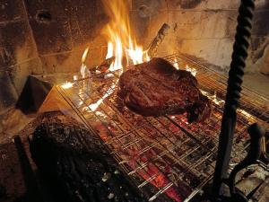 a piece of meat is cooking on a grill at castello di sovicille in Sovicille