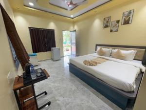 a bedroom with a large white bed and a table at Appa Hillside Nature Resort in Karjat +33 photos