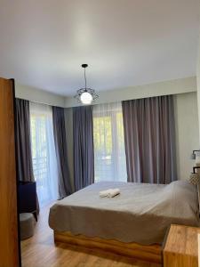 a bedroom with a large bed and windows at Likani Stay in Borjomi