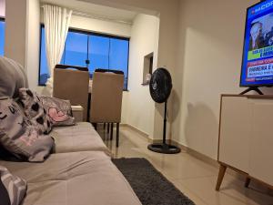 a living room with a tv and a couch and chairs at AP compartilhado Quarto aconchegante em Camboriú 10 min de BC in Camboriú