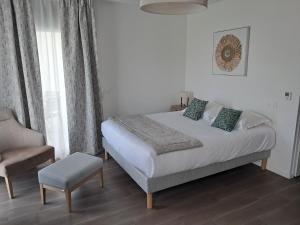 a bedroom with a bed and a chair in it at DOMITYS - Margot in Ploufragan