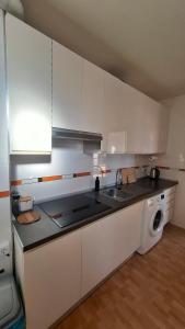 a kitchen with white cabinets and a washing machine at Vista al Mar in Piles