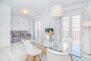 a white living room with a glass table and white chairs at Apartamentos Domus con parking gratuito in Granada