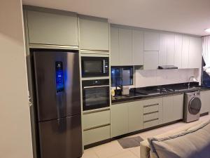a kitchen with a stainless steel refrigerator and appliances at AP compartilhado Quarto aconchegante em Camboriú 10 min de BC in Camboriú
