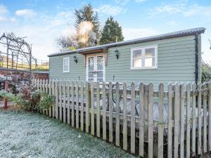 a small green house with a wooden fence at The Shepherds Rest - Uk45532 in Buildwas +7 photos