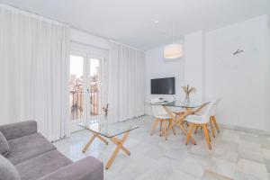 a living room with a couch and a table and chairs at Apartamentos Domus con parking gratuito in Granada