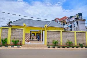 a yellow house with a fence in front of it at Marindo Lodge Moshi in Moshi