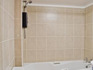 a bathroom with a shower with a bath tub at The Hen Hoose in Creebridge