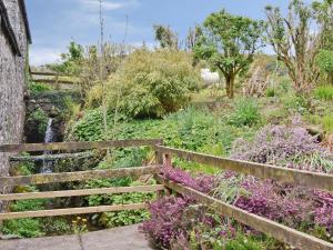 a wooden fence next to a garden with a waterfall at The Hen Hoose in Creebridge +5 photos