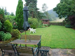 a picnic table with an umbrella on it in a garden at The Pottery Annexe in Baslow +4 photos