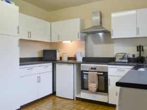 a kitchen with white cabinets and a stove top oven at Ribblestones in Austwick