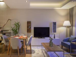 a living room with a table and a tv at Movenpick Living Istanbul West in Istanbul
