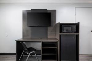 a desk with a tv and a microwave and a chair at Motel 6-Anaheim, CA - Convention Center in Anaheim