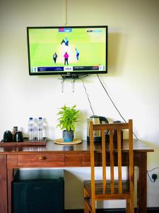 a television on a wall above a desk with a chair at Nature Luxe Sigiriya in Sigiriya