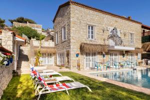 a villa with a swimming pool and lounge chairs at ALAÇATI ROKA TAŞ BUTİK HOTEL in Çeşme