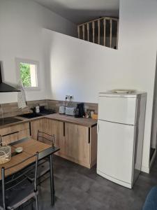 a kitchen with a white refrigerator and a table at L'escale Provençale in Pierrelatte