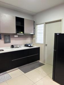 a kitchen with black cabinets and a black refrigerator at Sunset Retreat Sensory Residence in Kampung Dengkil