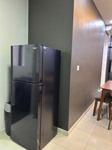 a black refrigerator in a room with a wall at Sunset Retreat Sensory Residence in Kampung Dengkil