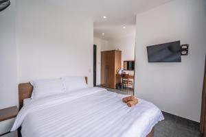 a bedroom with a large white bed with a stuffed animal on it at Mộc in Ấp Ða Lợi