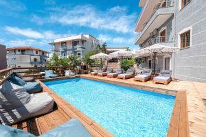 a swimming pool with chairs and umbrellas next to a building at Hotel Milo Ksamil in Ksamil