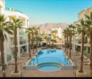 a swimming pool in a resort with palm trees and buildings at סוויטת לה פלמורה in Eilat