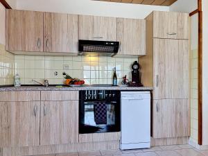 a kitchen with wooden cabinets and a white dishwasher at Apartment Sirch-2 by Interhome in Diedorf