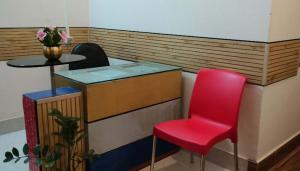 a red chair sitting next to a counter with a table at Hotel MeghTora in Goālpāra