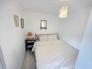 a small white bedroom with a bed and a lamp at Pam's Cottage in Cheltenham