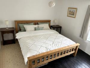 a bedroom with a large bed with a wooden frame at Pam's Cottage in Cheltenham +9 photos