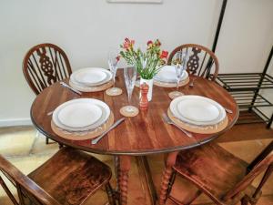 a wooden table with plates and utensils on it at Pam's Cottage in Cheltenham