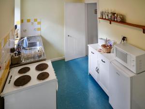 a small kitchen with a stove and a microwave at Pam's Cottage in Cheltenham
