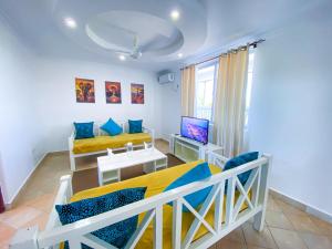 a small room with two beds and a tv at The Safiya Hotel, Diani Beach, "Formely Diani Palm Resort" in Diani Beach