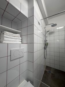 a white tiled bathroom with a shower and towels at Stresa Complex LevOasi in Stresa