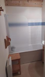 a bathroom with a white bath tub and a wooden stool at Studio plein sud avec piscine in Saint-Jean-dʼArves