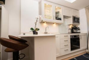 a kitchen with white cabinets and a sink at Garden Studio in Hove, Parking & Hot Tub in Brighton & Hove