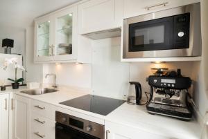 a white kitchen with a sink and a microwave at Garden Studio in Hove, Parking & Hot Tub in Brighton & Hove