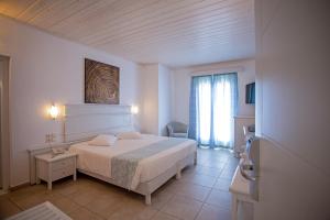 a white bedroom with a bed and a window at Yiannaki Hotel in Ornos +127 photos