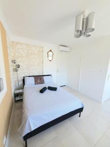 a white bedroom with a bed with shoes on it at Cannes Centre Studio Lumineux et Chic, à 9 Min à Pied du Palais des Festivals et des Plages, Clim in Cannes