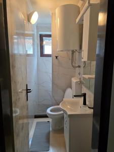 a white bathroom with a toilet and a sink at Studio Lanterna in a seaside house in Dobrota