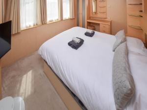 a bedroom with a white bed with a bag on it at Fellside Lodge in Cockermouth +6 photos