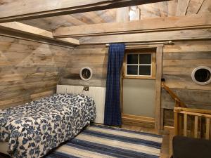 a bedroom with a bed in a room with wooden walls at Tolvmansgården in Enköping